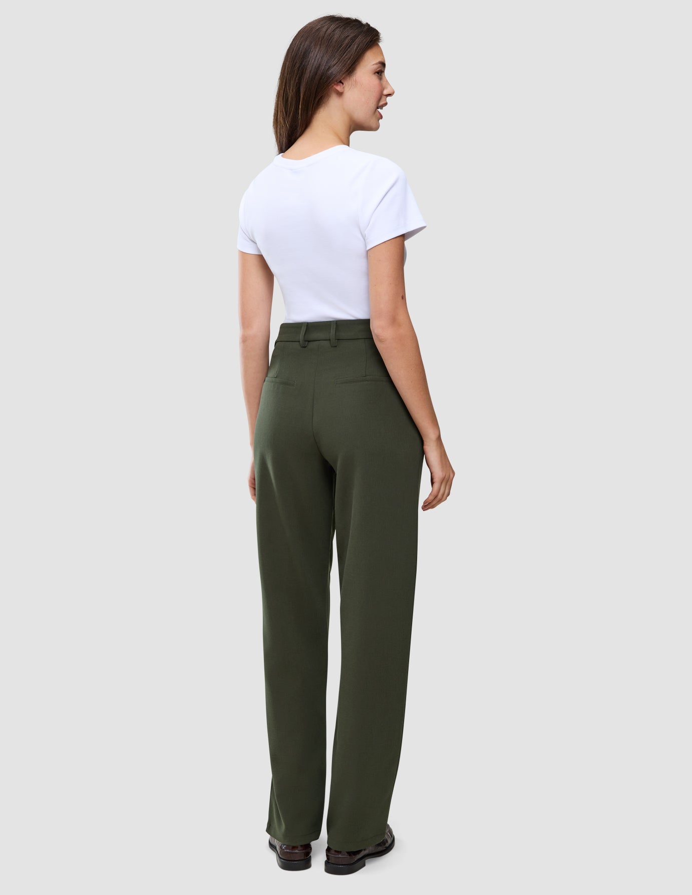 Rückansicht einer Frau, die ein weißes T-Shirt und die Hose Women GO2 Pants Straight Dusty Olive trägt, die sich durch eine klare, skandinavische Designästhetik auszeichnet.